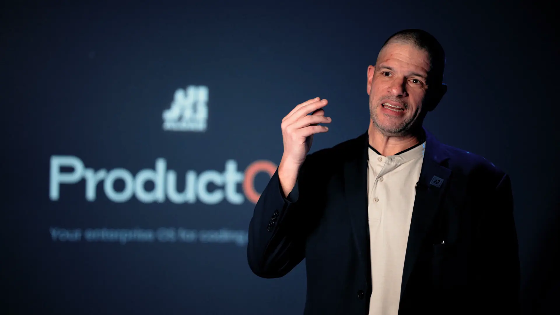 Tony Pagliocco speaking in front of the ProductOS display